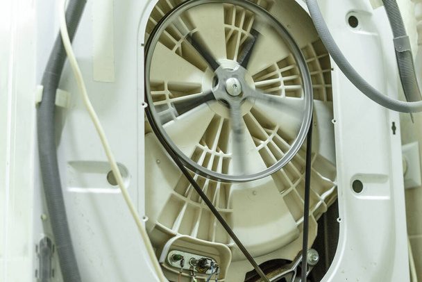 Pesukoneen hihnapyörä rummussa suurilla nopeuksilla käytön aikana. Kodinkoneiden korjaus - Valokuva, kuva