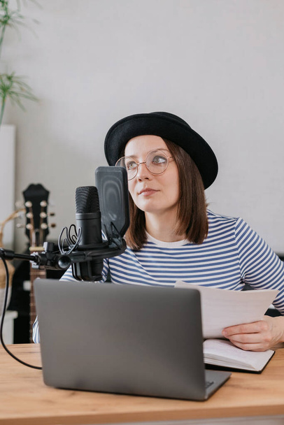 podcast, audio content creation. a beautiful European woman podcaster or radio host records a podcast or content in a recording studio - 写真・画像