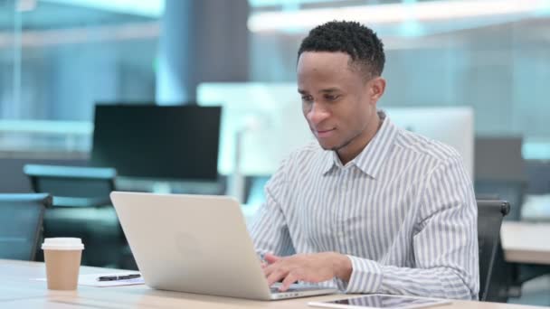 Pulgares hacia arriba por el empresario africano con el ordenador portátil en el trabajo  - Metraje, vídeo