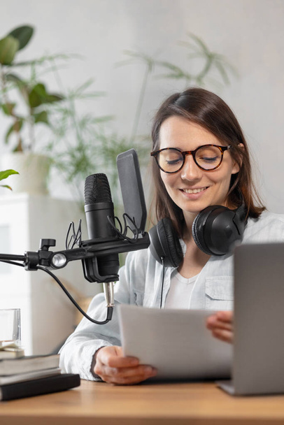 podcast, audio content creation. a beautiful European woman podcaster or radio host records a podcast or content in a recording studio - Foto, immagini