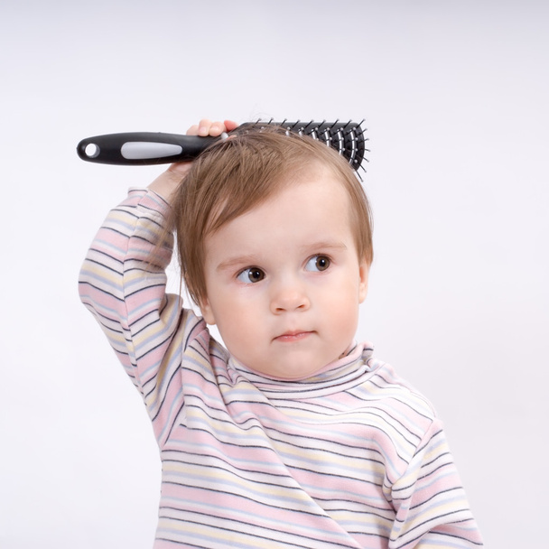 Cute little baby playing with a hairbrush - Fotoğraf, Görsel