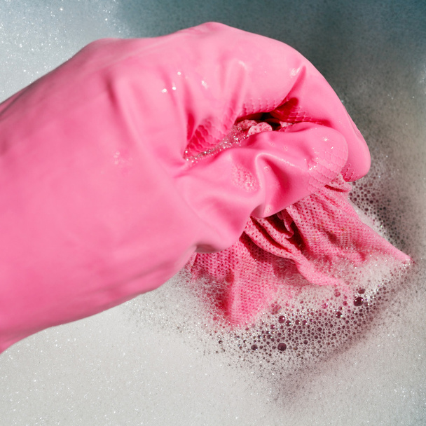 Hand in rosa Gummihandschuh ringt nasses Tuch aus - Foto, Bild