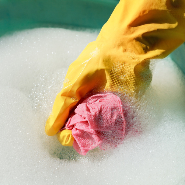 mano en guante de goma amarillo enjuague plumero húmedo
 - Foto, imagen
