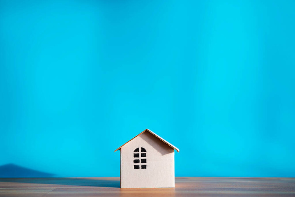 Diseño de casa de papel blanco aislado sobre fondo azul, sombras que muestran calidez. El espacio vacío puede incluir texto publicitario. - Foto, imagen