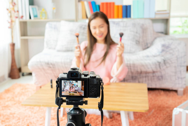 Young beautiful Asian woman professional beauty vlogger or blogger recording make up tutorial to share on social media. Young beauty blogger recording video at home - Foto, imagen