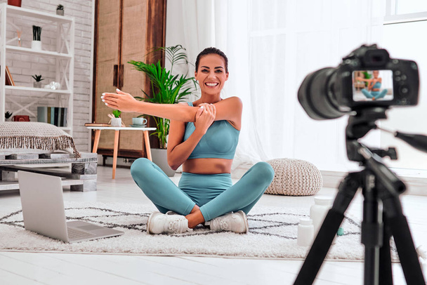 Young female blogger recording sports video at home. Stay at home activities. Prevent infection from the pandemia. - Fotoğraf, Görsel
