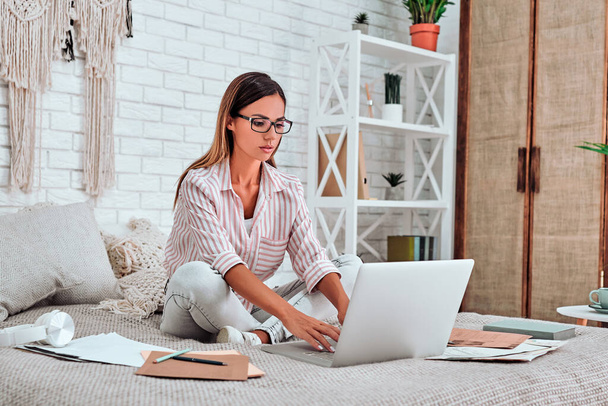 Distance learning online education and work. Happy businesswoman working office work remotely from home on bed. - Φωτογραφία, εικόνα