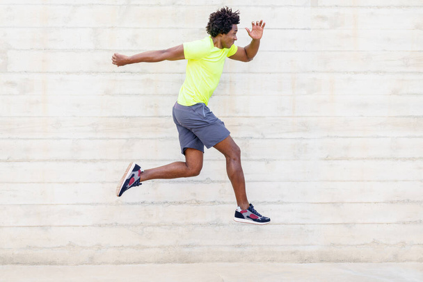 Black man training running jumps to strengthen his legs. - Zdjęcie, obraz