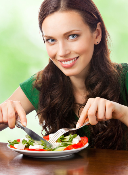 Portrait de femme souriante heureuse mangeant de la salade dans une assiette, en plein air
 - Photo, image