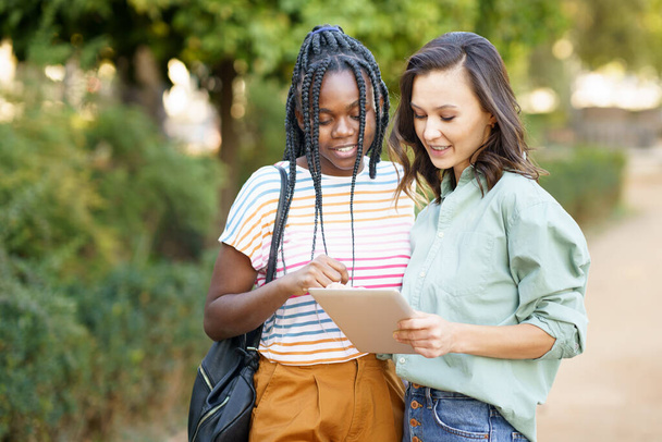 Deux femmes multiethniques consultant quelque chose sur une tablette numérique. - Photo, image