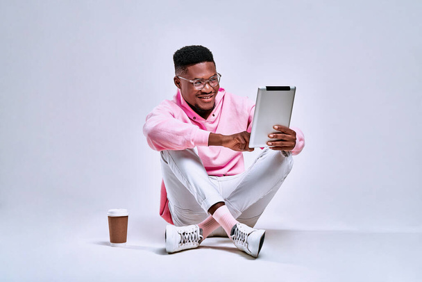 Handsome african american stylishly dressed holding a tablet and chatting online with friends. Conceptual fun, lifestyle and accessories. - Φωτογραφία, εικόνα