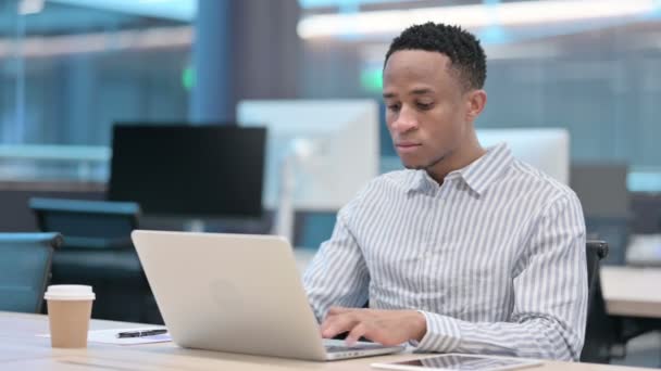 Jeune homme d'affaires africain travaillant sur ordinateur portable au bureau  - Séquence, vidéo