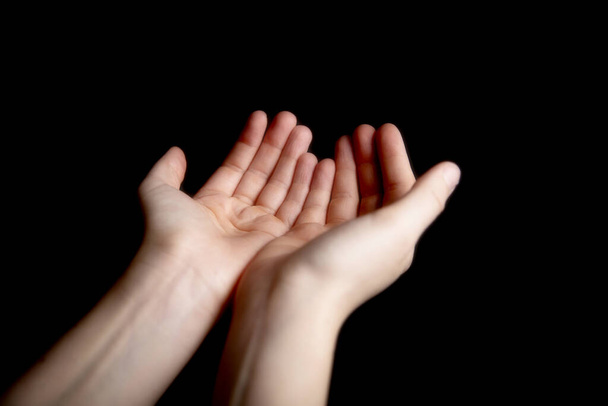 Otevřené ruce gesto pro žebrání nebo modlení na tmavém černém pozadí, víra, pomoc, uctívač znamení koncept - Fotografie, Obrázek