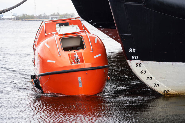 Imbarcazione di salvataggio completamente chiusa galleggiante vicino a grande imbarcazione - Foto, immagini