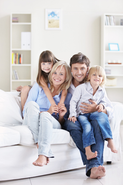 Une famille heureuse avec des enfants sur un canapé blanc à la maison
 - Photo, image