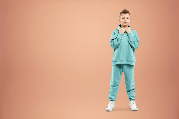 Portrait, cute stylish boy in a blue suit on a beige background. Studio portrait of a child, modern design, trendy background, turquoise. Copy space - Fotó, kép