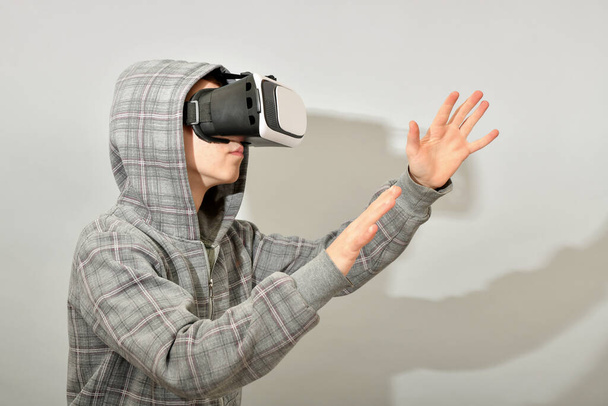 A teenager in a VR helmet is surprised by the immeasurable reality in the virtual world. - Foto, imagen