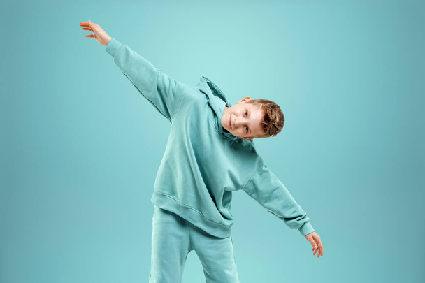 Portrait, cute stylish boy in a blue suit on a blue background. Studio portrait of a child, modern design, trendy background, turquoise. Copy space - Fotó, kép