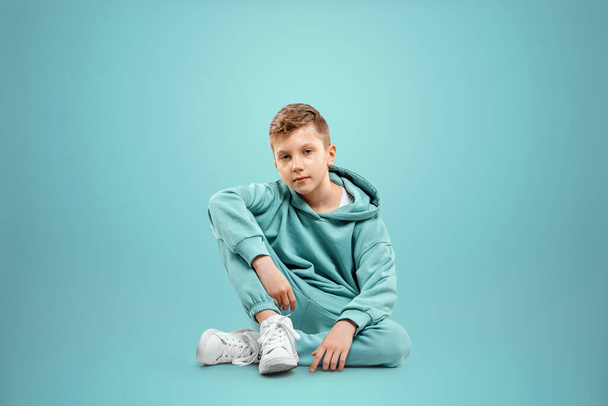 Portrait, cute stylish boy in a blue suit on a blue background. Studio portrait of a child, modern design, trendy background, turquoise. Copy space - Zdjęcie, obraz