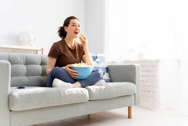 Young woman watching  TV, movies with popcorn. Girl spending time at home. - Фото, изображение