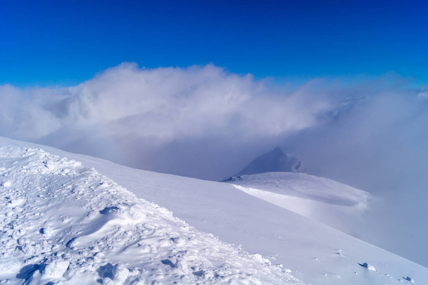 snow in the mountains, fog in the distance, blue sky - Фото, изображение