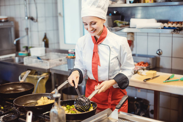 Mujer chef con sartenes y ollas preparando comida en la cocina del restaurante - Foto, Imagen