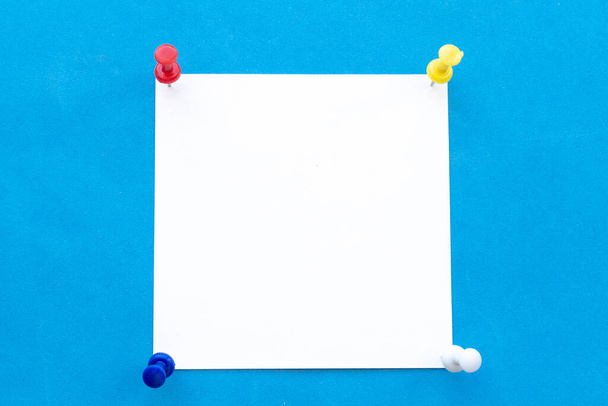 Fehér jegyzetfüzet négy többszínű tűvel kék alapon - Fotó, kép