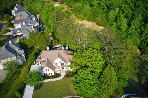 A beautiful Panoramic aerial view of cluster of beautiful houses, landscaped yards and fresh spring bloom on trees in an upscale subdivision in Suburbs of Georgia shot during golden hour. - Photo, Image