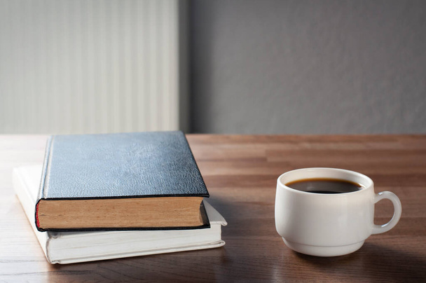 Zwei Bücher auf einem Holztisch. Ein Stapel Bücher. Eine Tasse Kaffee. Arbeitsplatz. - Foto, Bild