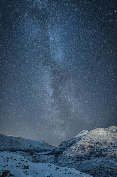 A vertical shot of a beautiful snowy landscape under the Milky Way sky background - Foto, Bild