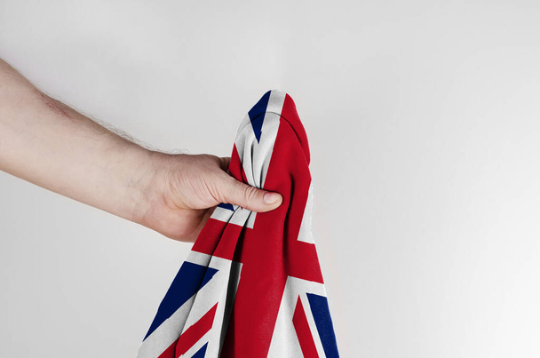 Державний прапор Великої Британії в руках на білому тлі. Один чоловік тримає прапор Сполученого Королівства Великої Британії та Північної Ірландії. Сторона зору. - Фото, зображення
