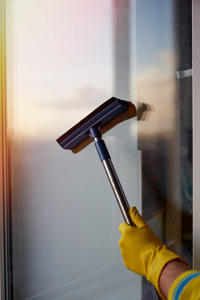 Καθαρισμός σπιτιού την άνοιξη. Πλένω παράθυρα. Οικιακές δουλειές, ένας άντρας καθαρίζει το σπίτι του. Απολύμανση κατά τη διάρκεια της καραντίνας λόγω coronavirus. - Φωτογραφία, εικόνα
