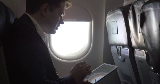 Junger Geschäftsmann arbeitet mit Polster im Flugzeug - Foto, Bild