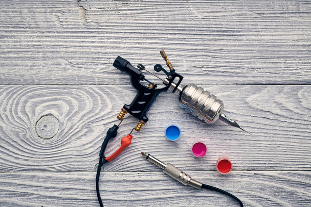Tattoo machine, tools and supplies over wooden background. Tattoo studio. - Photo, Image
