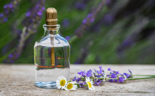 Olie essentie fles en lavendel bloemen op rustieke houten achtergrond. Vintage filterafbeelding. - Foto, afbeelding