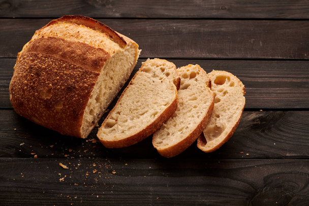 Frissen sütött házi tartányos kenyér sötét fa asztalon - Fotó, kép