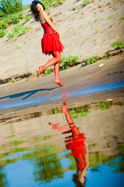 Girl dressed in red dress on a coast - Photo, Image