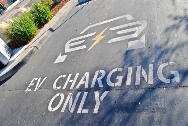 Electronic Vehicle charging station parking spot. Paint on asphalt. EV charging only 2 hour limit. Also called EV charging station, electric recharging point, charge point. - Photo, Image