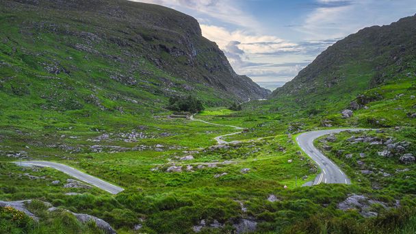 Piękny krajobraz z krętą wąską drogą biegnącą przez przepaść Dunloe i Czarną Dolinę, góry MacGillycuddys Reeks, Pierścień Kerry, Irlandia - Zdjęcie, obraz
