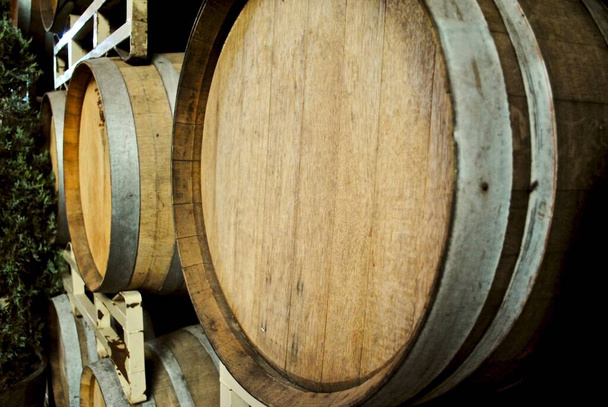 Barricas de vino de madera apiladas o barricas en Ironstone Vineyards en California. Enfoque selectivo con distancia borrosa. Espacio para texto. Cabezales de madera y carillón, el borde biselado al final de cada pentagrama. - Foto, imagen
