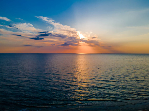 Hermosa puesta de sol colorida entre las nubes sobre un mar ligeramente ondulado - Foto, Imagen