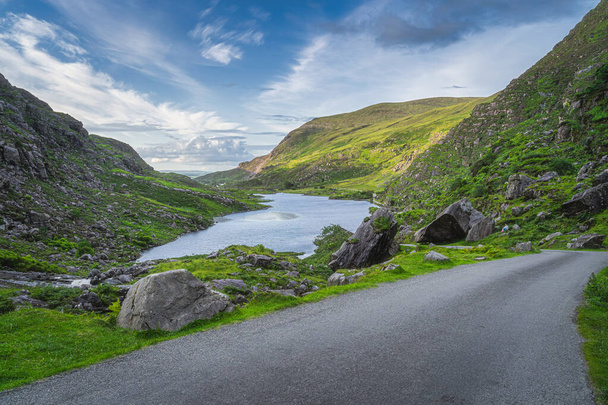Piękny krajobraz z jeziorem, zielone wzgórza i kręta droga w Gap Dunloe, Czarna Dolina, Góry MacGillycuddys Reeks, Pierścień Kerry, Irlandia - Zdjęcie, obraz