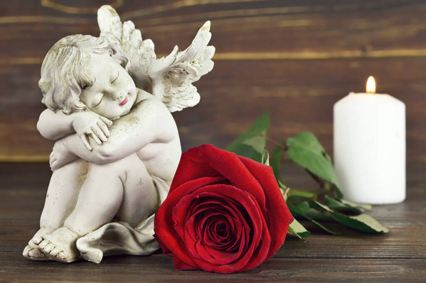 Kondolenzkarte mit Engel, roter Rose und weißer brennender Kerze auf Holzgrund - Foto, Bild