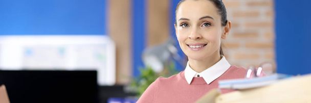 Portrait of a smiling woman at a work table with documents - Foto, Imagen