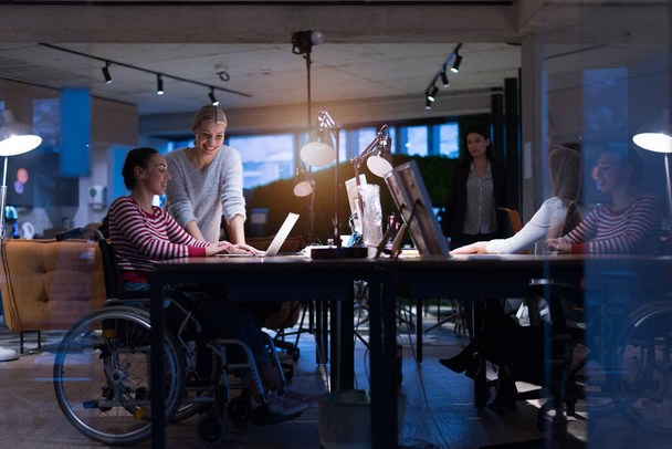 Счастливые рабочие весело провели время в современном офисе, инвалид на коляске. Общение с коллегами. Концепция командной работы и инвалидности - Фото, изображение