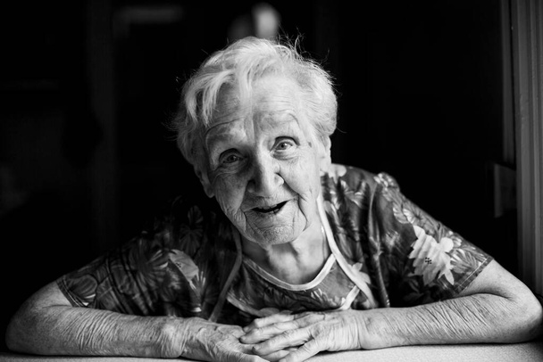 Portrait of an old woman sitting in her home. Black-and-white photo. - Foto, Bild