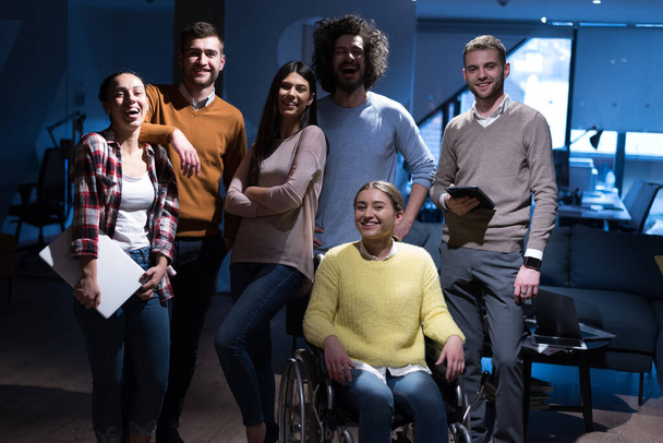 Счастливые рабочие весело провели время в современном офисе, инвалид на коляске. Общение с коллегами. Концепция командной работы и инвалидности - Фото, изображение