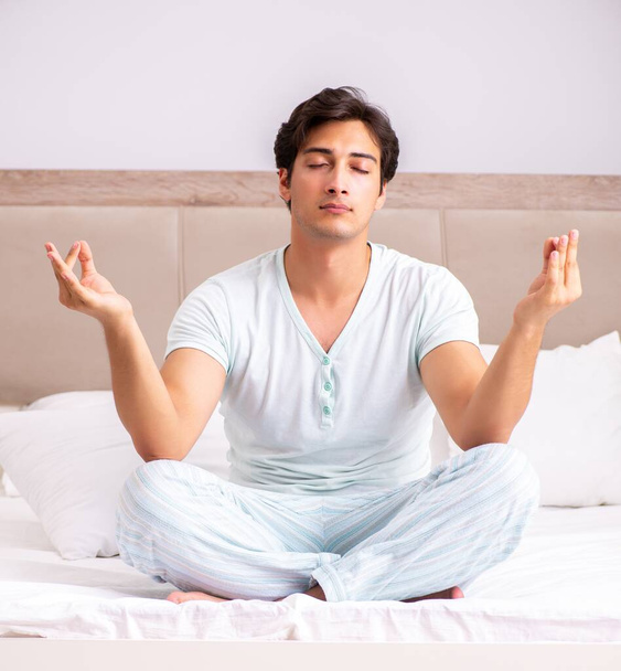 Junger Mann macht Yoga im Bett - Foto, Bild