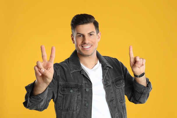 Man showing number three with his hands on yellow background - Foto, imagen