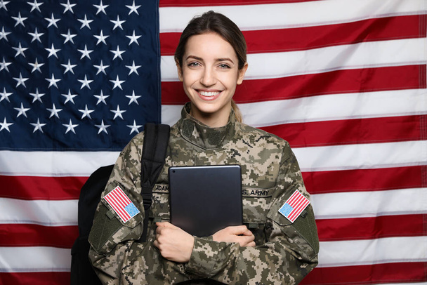 Female cadet with backpack and tablet against American flag. Military education - Photo, image